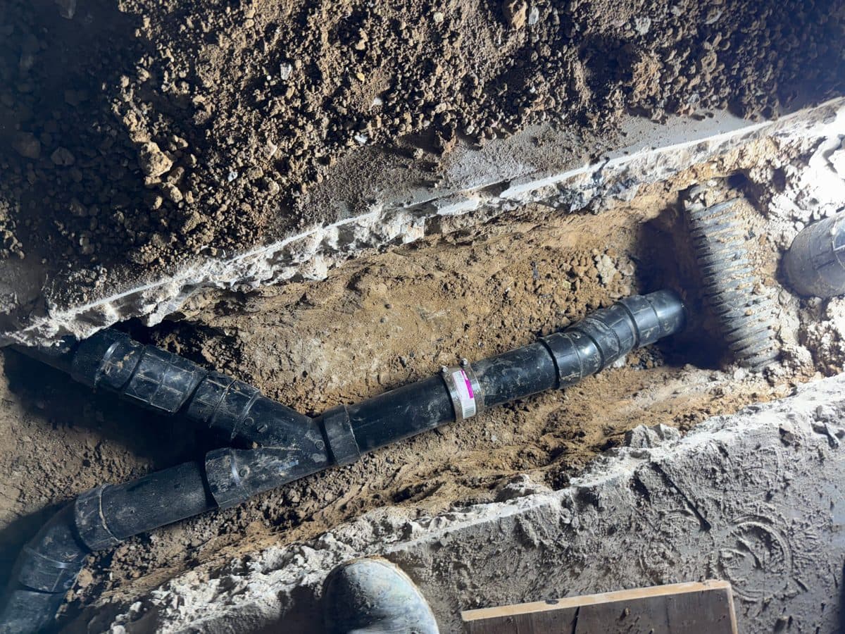 After: new ABS sewer pipe installed with proper fittings and clean connections