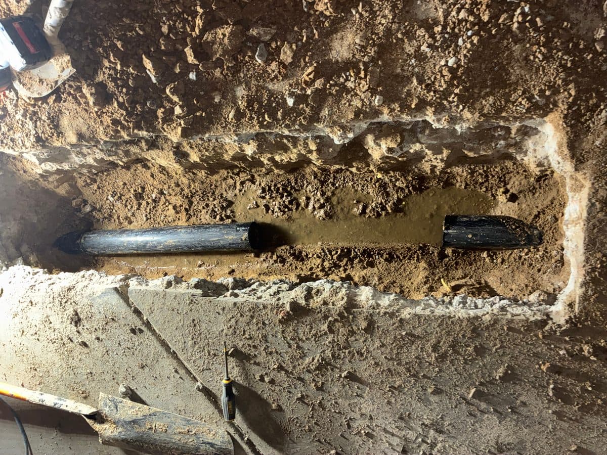 Before: excavated sewer trench showing old deteriorated cast iron sewer pipe in Denver home